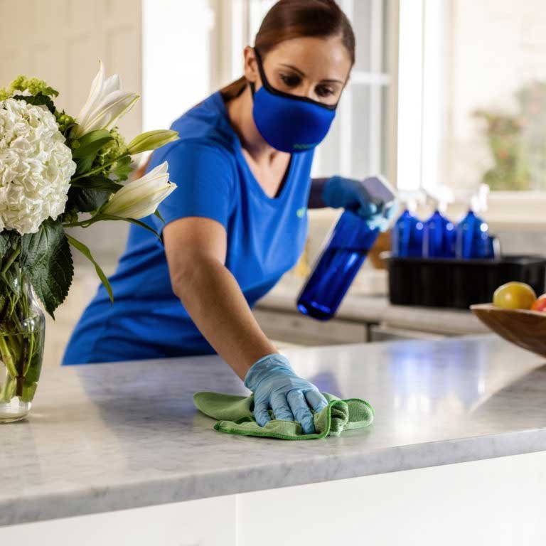 Cleaning service professional wiping a kitchen countertop.